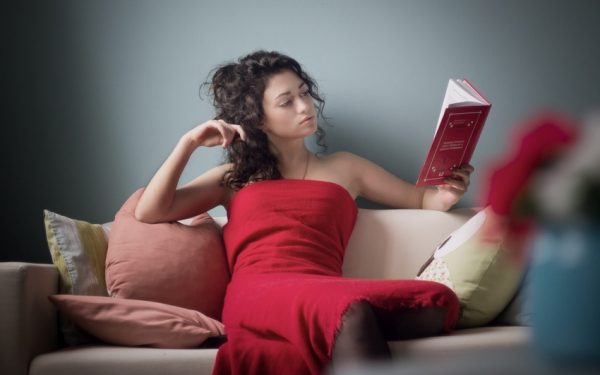 Девушка на диване читает книгу