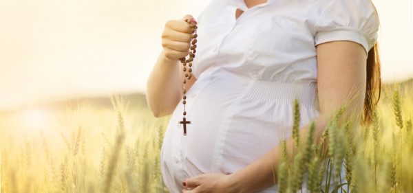 Беременная с крестоком в руках