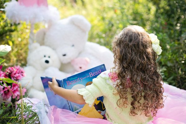 Девочка читает сказку игрушкам