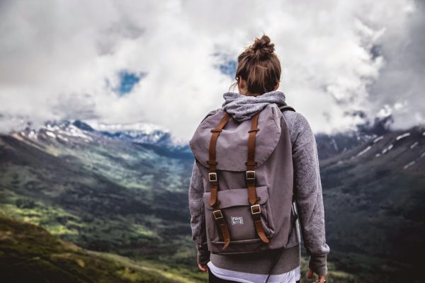 Девушка с рюкзаком на вершине горы