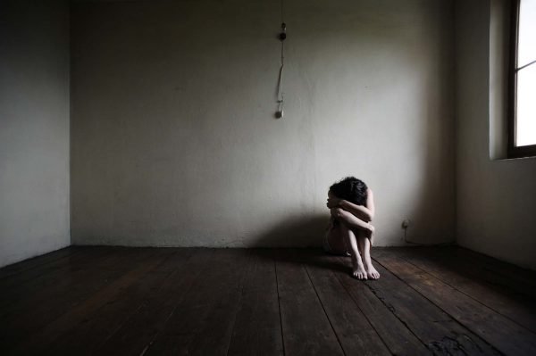 Девушка сидит на полу в пустой комнате