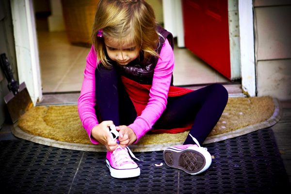 Девочка завязывает шнурки