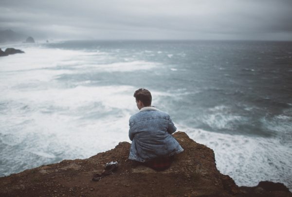 Мужчина сидит в одиночестве на берегу моря