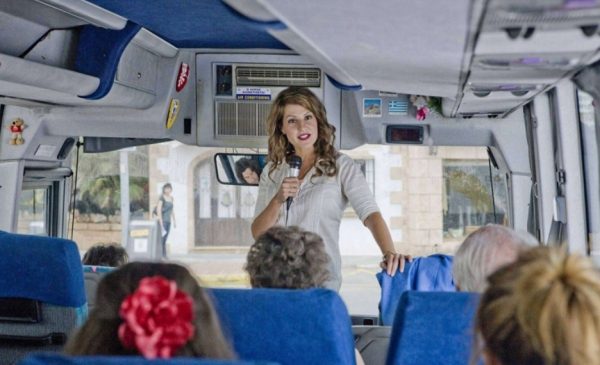 Женщина-гид в автобусе говорит в микрофон